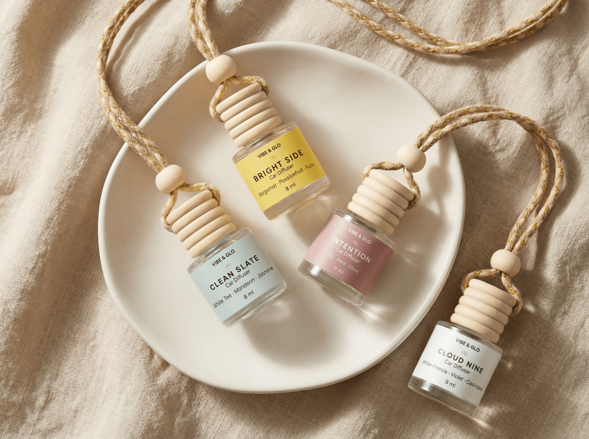 Flatlay of refillable car diffusers in multiple scents on a neutral background representing non-toxic car air freshener alternatives and long-lasting car fragrance