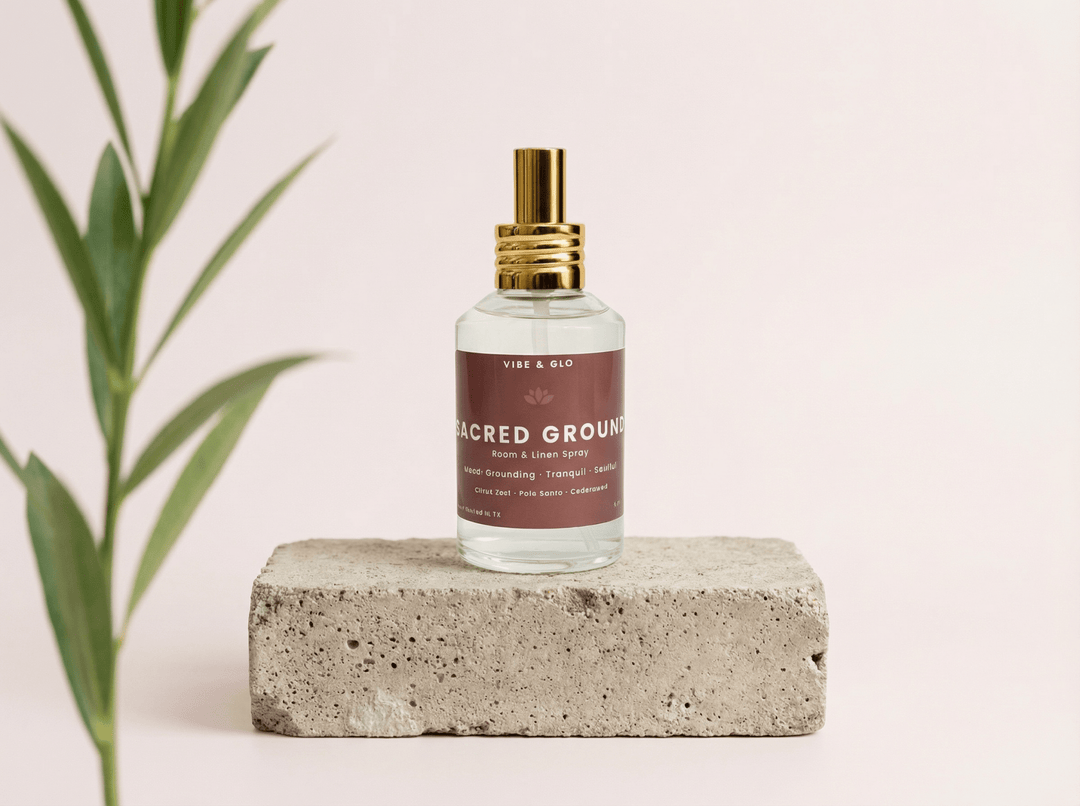 Sacred Ground room and linen spray by Vibe & Glo displayed on a stone block with greenery, featuring a clean, grounding home fragrance aesthetic