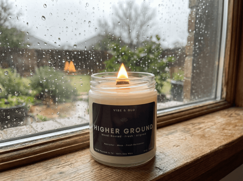 Clean-burning Vibe & Glo soy candle glowing by a rainy window creating a cozy non-toxic home fragrance atmosphere.
