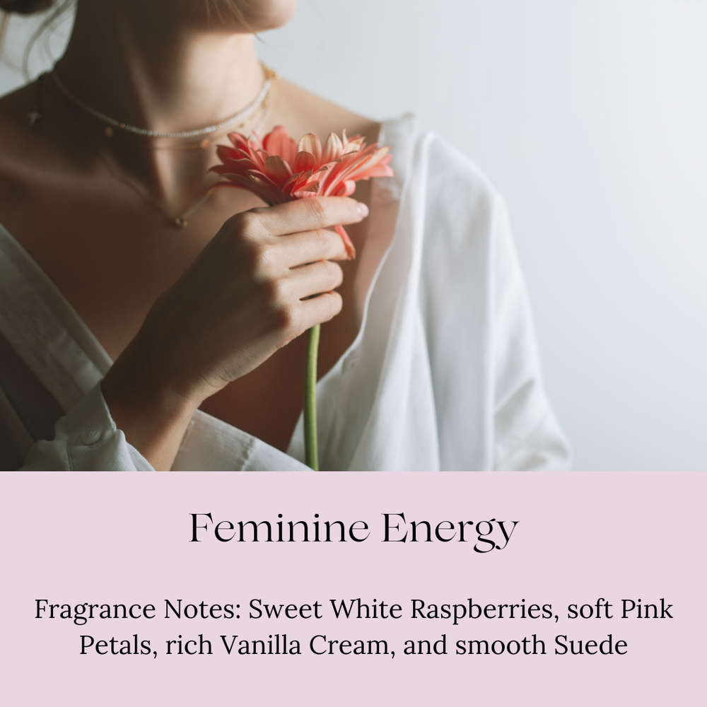 
                      
                        A woman in a soft white shirt gently holds a pink flower near her face, creating a serene and feminine mood. The text below reads 'Feminine Energy' with fragrance notes of sweet white raspberries, soft pink petals, rich vanilla cream, and smooth suede.
                      
                    