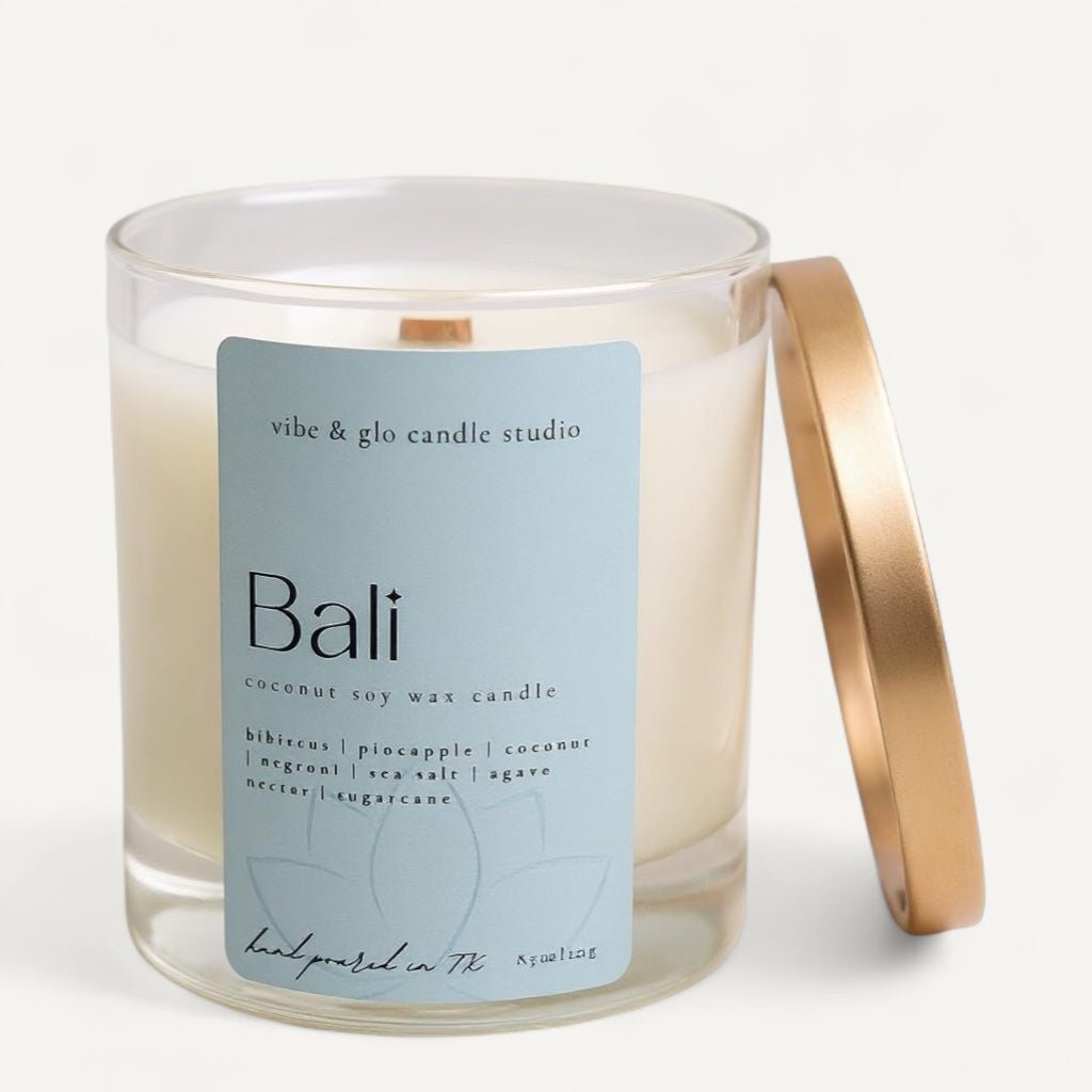 Vibe & Glo Bali candle featuring hibiscus, pineapple, coconut, negroni, sea salt, agave nectar, and sugarcane scents in a clear glass jar with gold lid.