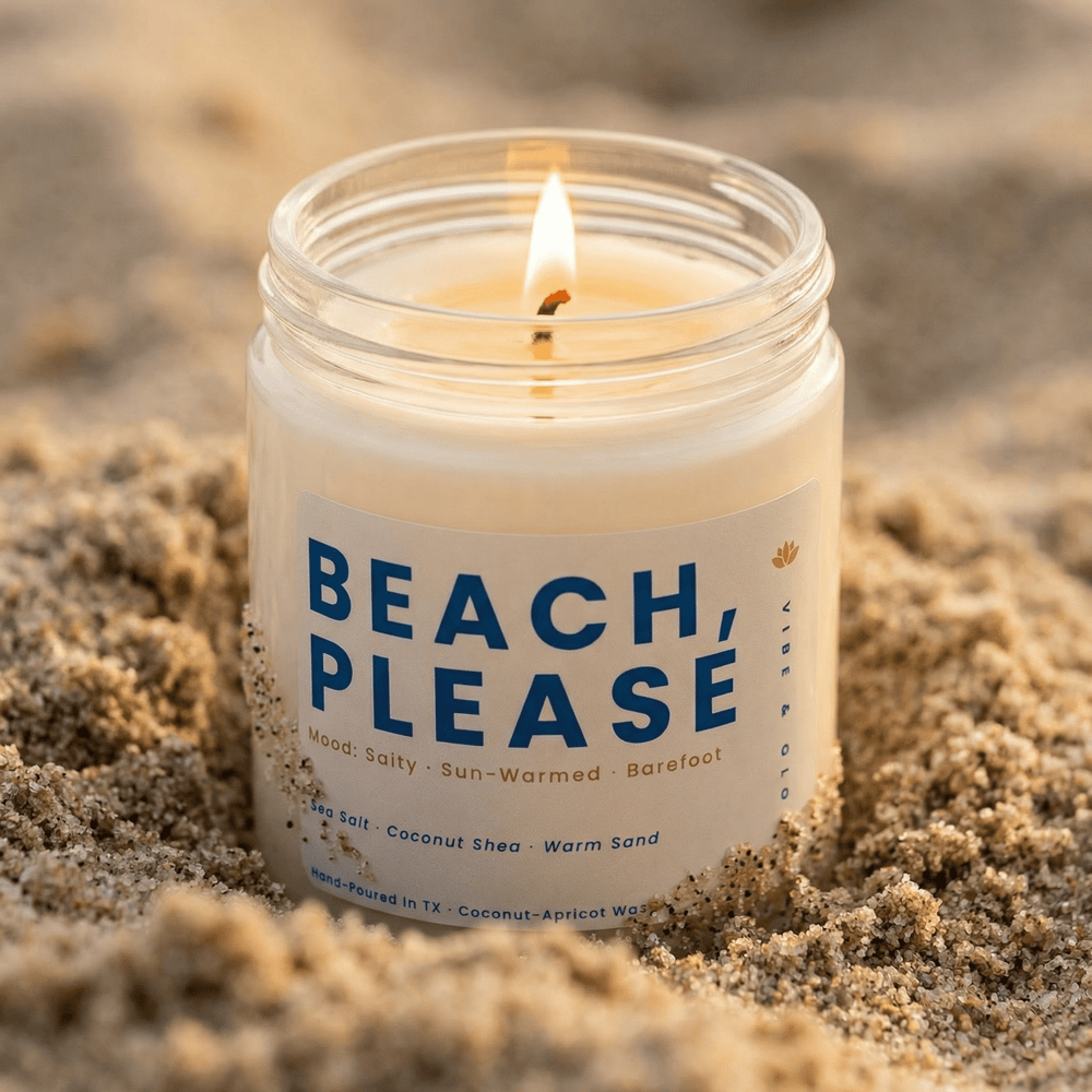 Beach scented candle placed in sand with a warm glowing flame, creating a coastal summer vibe