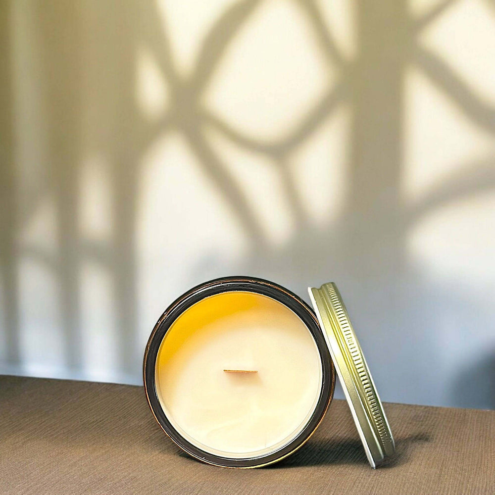 
                      
                        A top-down view of an opened "Creekside Cabin" candle, showing smooth wax and a wooden wick. The candle rests on a brown surface with soft, natural lighting casting intricate shadows on the wall.
                      
                    