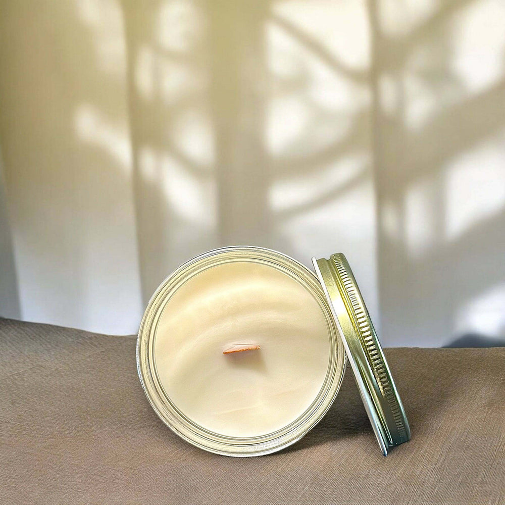 
                      
                        A top-down view of the opened "Eucalyptus & Spearmint" candle, showing smooth wax with a wooden wick at the center. The candle is resting on a soft fabric surface, with natural light casting delicate patterns of shadows on the wall behind.
                      
                    