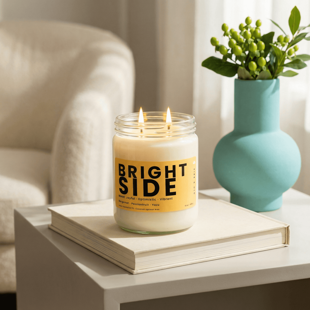 Bright Side 2-wick candle on a book beside a vase in a bright modern living space, clean fresh home fragrance