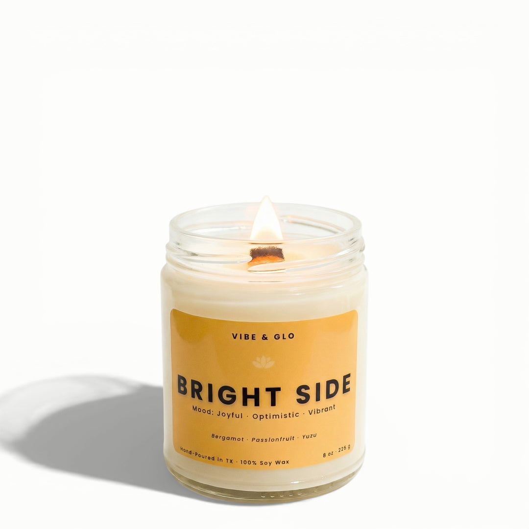Bright Side citrus soy candle with bergamot, passionfruit, and yuzu by Vibe & Glo featuring a lit wooden wick in clear jar.