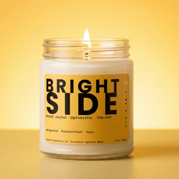 Bright Side coconut apricot wax candle burning in a clear glass jar with a bright citrus fragrance of bergamot passionfruit and yuzu