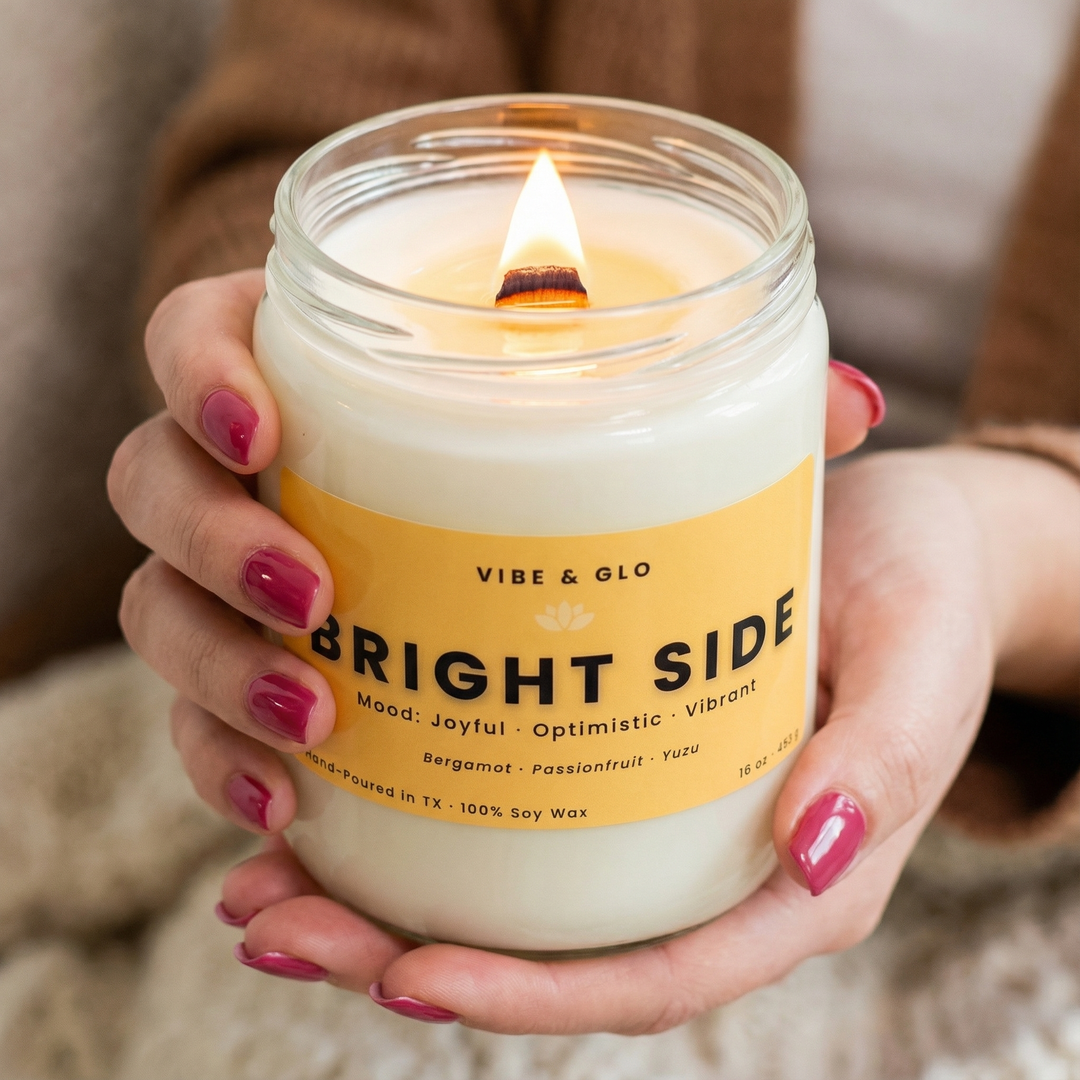 Bright Side soy candle by Vibe & Glo lit with a wooden wick, held in hands in a bright, cheerful lifestyle scene