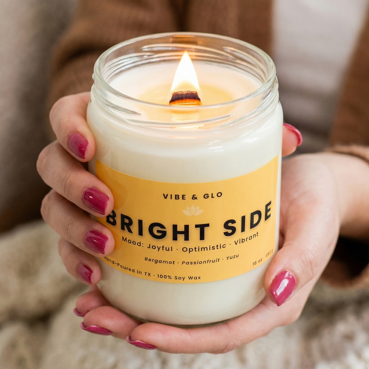 Bright Side soy candle by Vibe & Glo lit with a wooden wick, held in hands in a bright, cheerful lifestyle scene