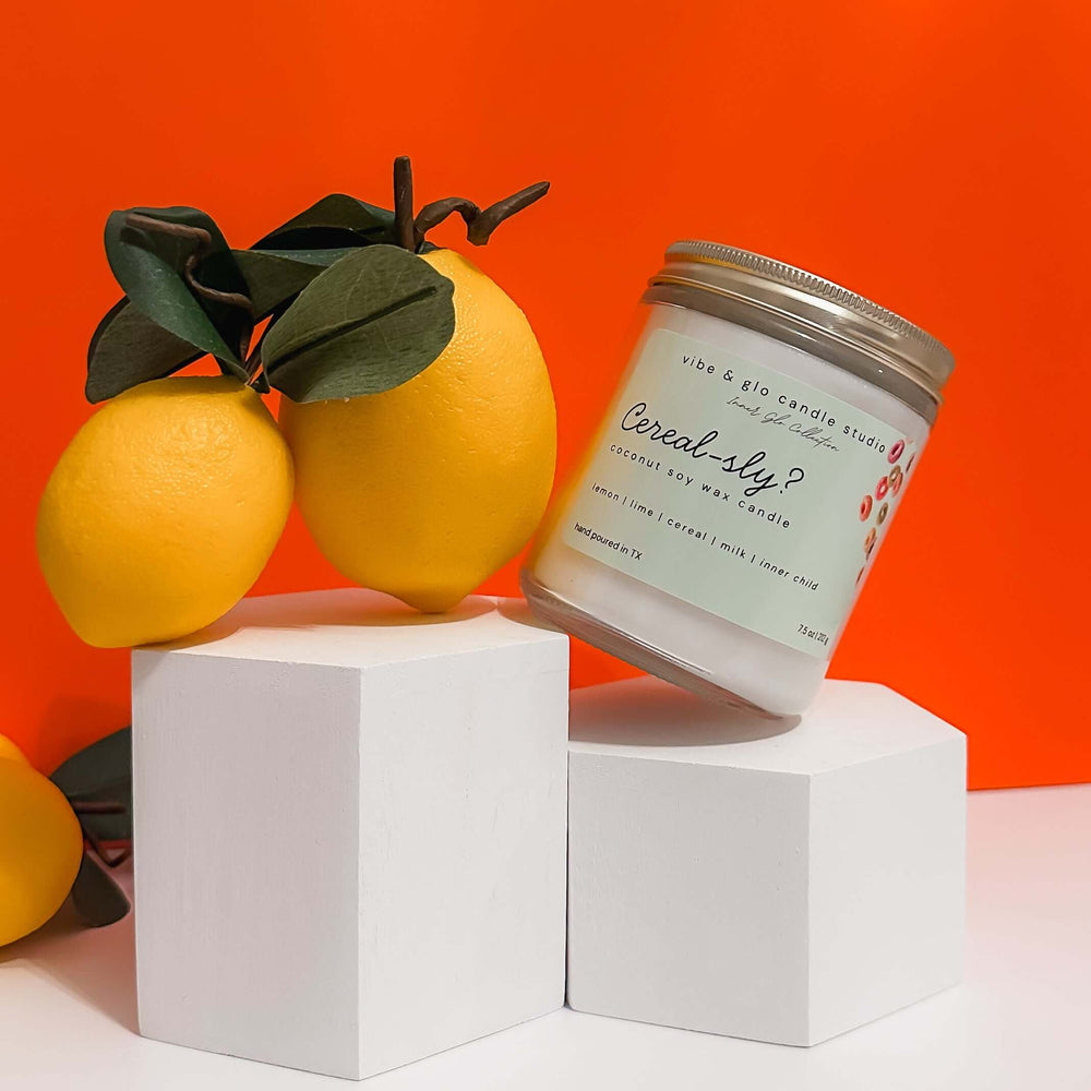 Cereal-sly? coconut soy wax candle close-up with lemons on an orange backdrop.