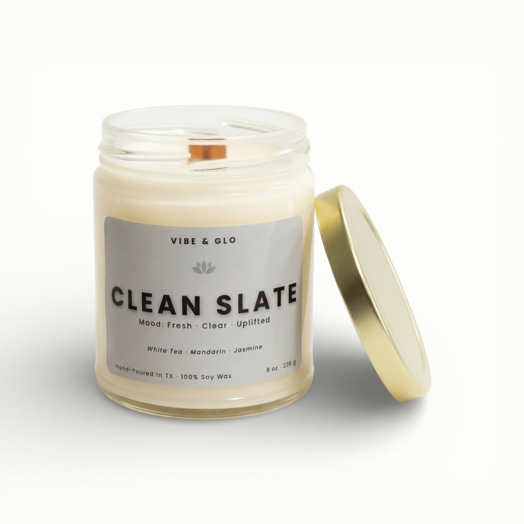 Vibe & Glo Clean Slate soy candle in clear glass jar with wooden wick and gold lid, white tea mandarin and jasmine scent