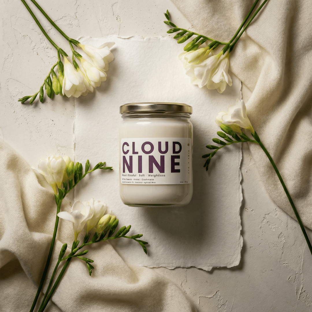 Cloud Nine candle styled with white freesia flowers on textured neutral background, soft floral clean scented candle
