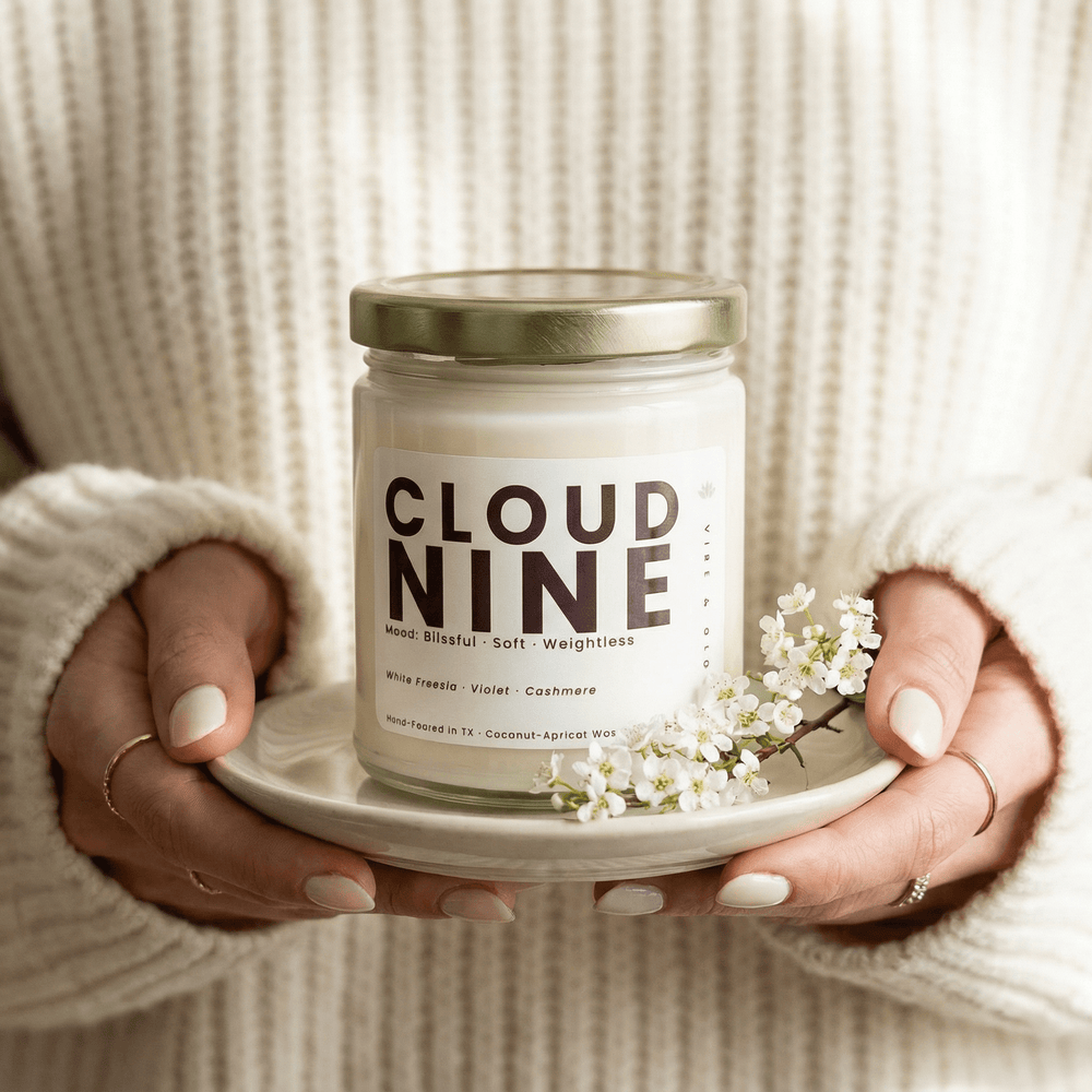 Cloud Nine candle held in hands on a ceramic plate with delicate flowers creating a cozy self care moment with a soft floral scent