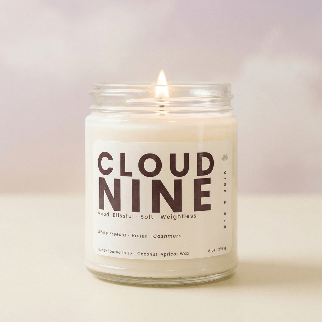 Cloud Nine natural wax candle burning in a clear glass jar with soft neutral background highlighting a clean soft floral scent