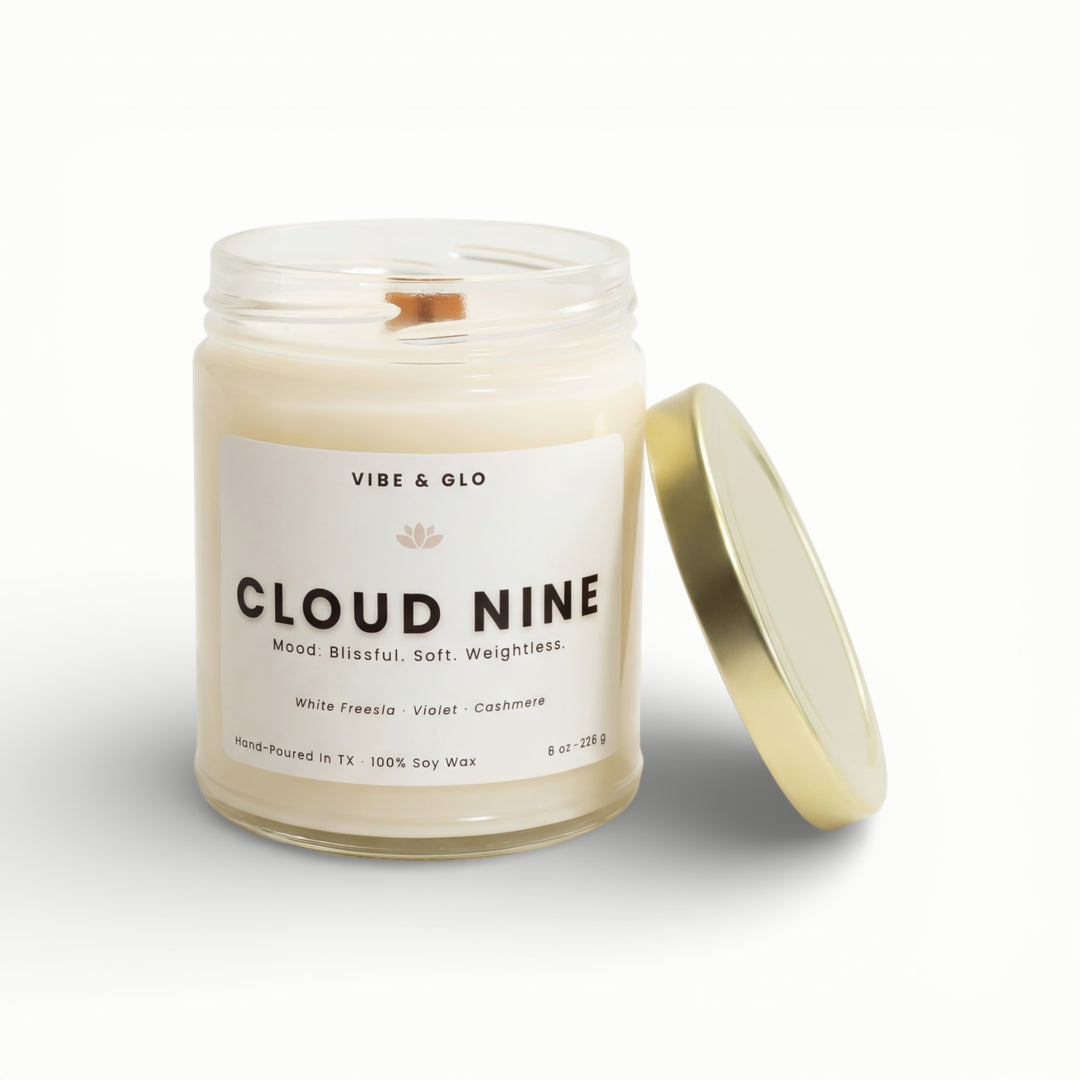 Vibe & Glo Cloud Nine soy candle in clear glass jar with wooden wick and gold lid, white freesia violet and cashmere fragrance