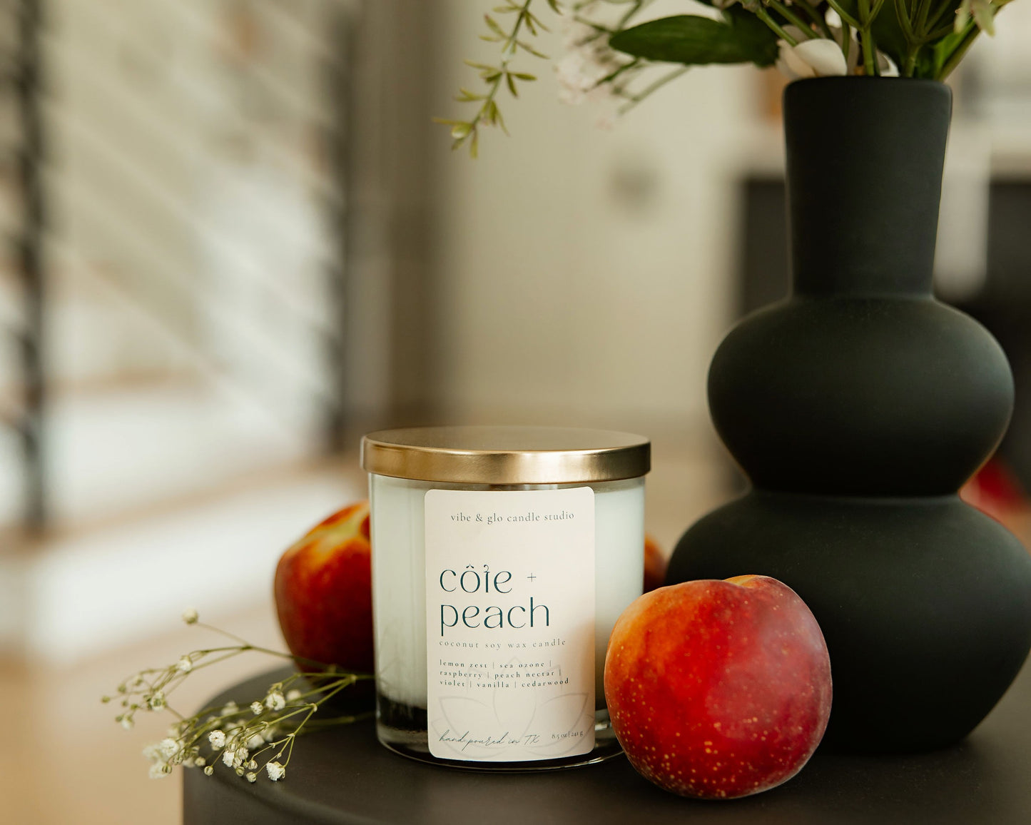 Cote Peach candle with peaches and a vase in the background