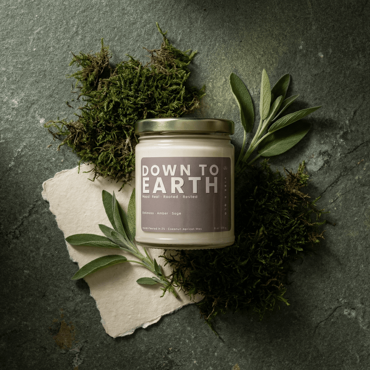 Down to Earth candle styled with oakmoss and sage in an earthy botanical flatlay representing grounding natural scents