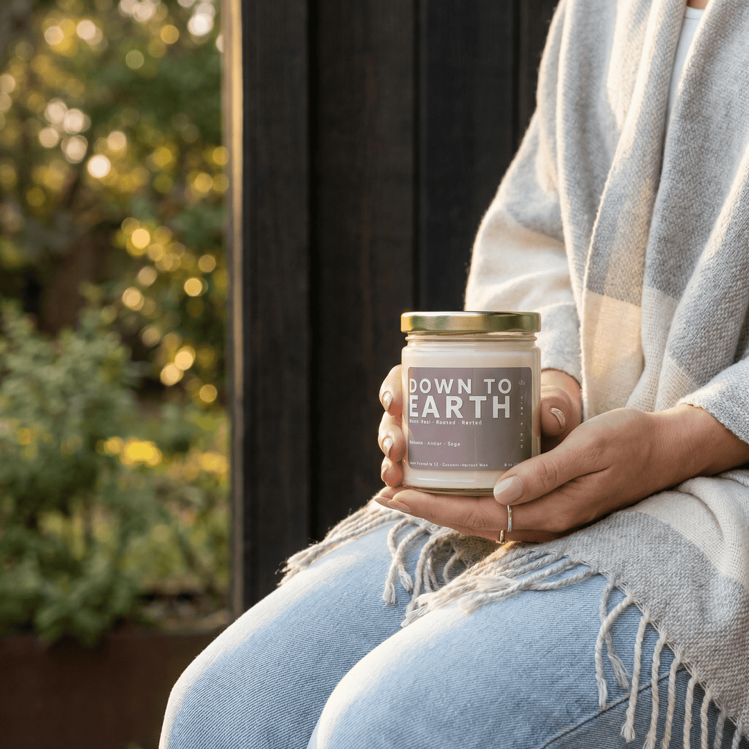 Down to Earth candle held outdoors with cozy blanket creating a warm grounding fall-inspired lifestyle scene