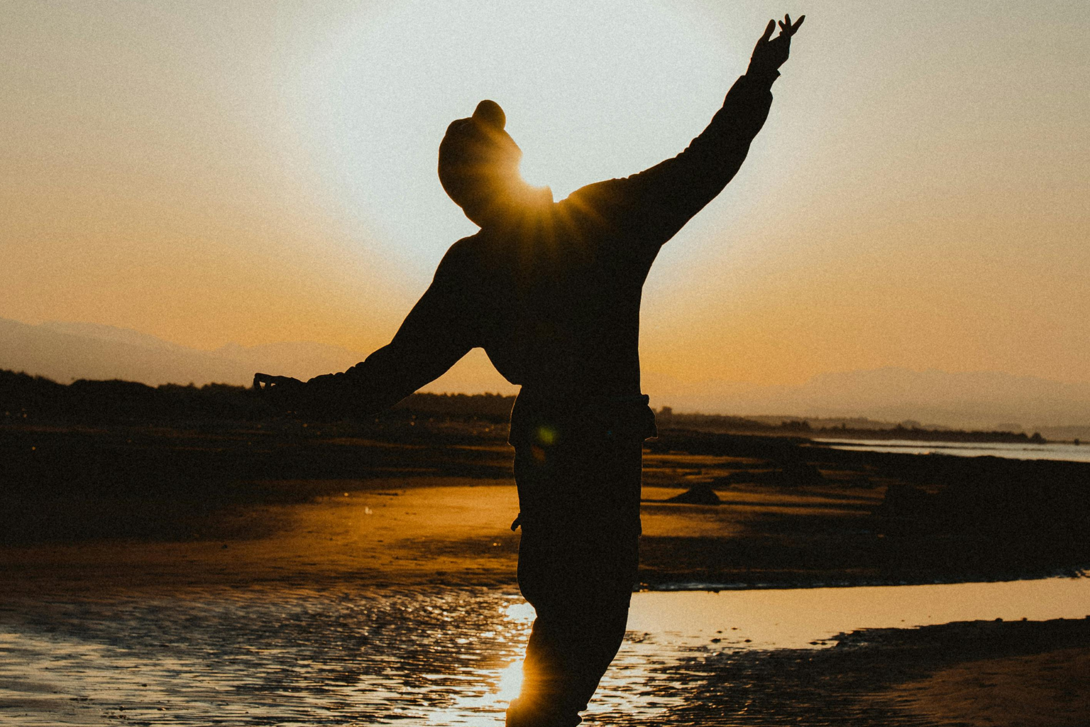 Person standing in golden sunrise light with arms raised, symbolizing energizing candles, fresh uplifting scents, and mood-boosting home fragrance.