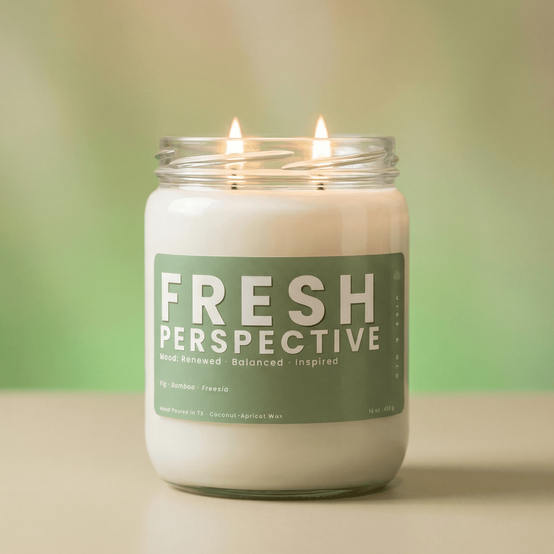 Fresh Perspective 2-wick candle glowing against soft green background, clean fresh candle with bamboo and freesia scent