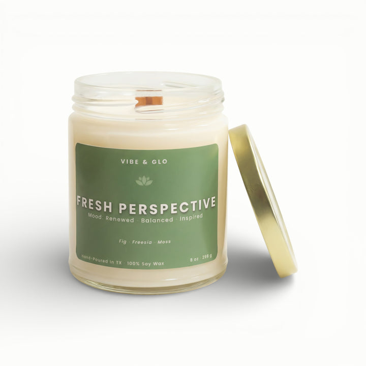 Vibe & Glo Fresh Perspective soy candle in clear glass jar with wooden wick and gold lid, fig freesia and moss fragrance