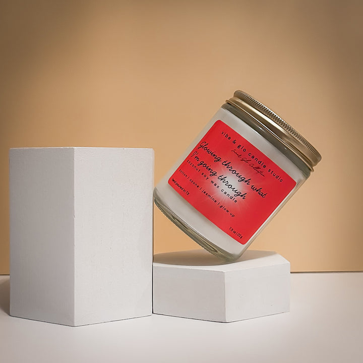 Glowing through what I’m going through coconut soy wax candle with cotton, ozone, and jasmine. Displayed at an angle on white blocks for a minimal, modern aesthetic.

