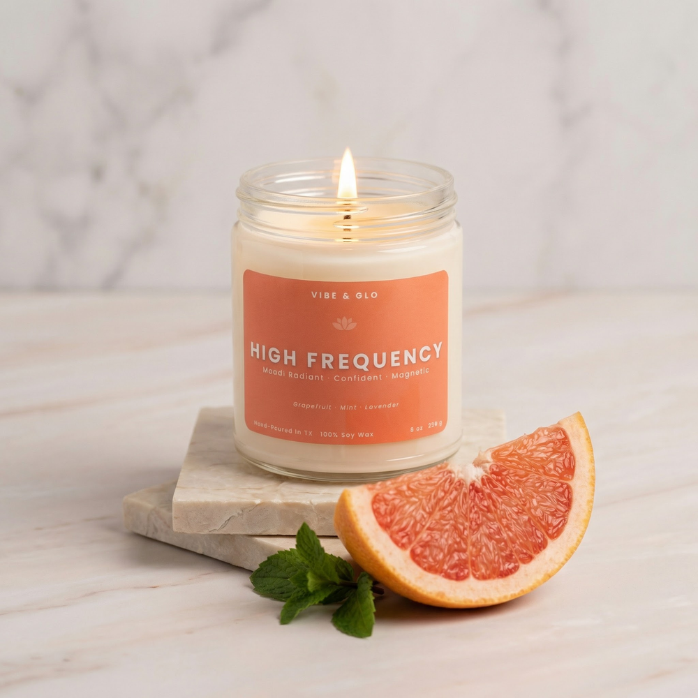 High Frequency grapefruit mint lavender soy candle in glass jar, lit on marble surface with fresh grapefruit slice and mint leaves, bright citrus home fragrance.