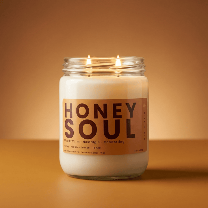 Honey Soul 2-wick honey & tobacco candle with two cotton wicks burning against a warm golden background, cozy modern product image