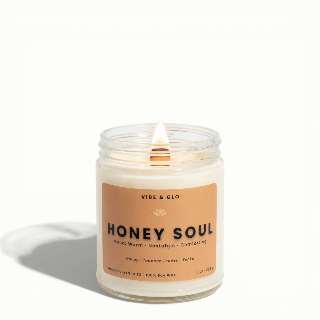 Honey Soul honey, tobacco leaves, and tonka soy candle by Vibe & Glo with lit wooden wick in clear glass jar.
