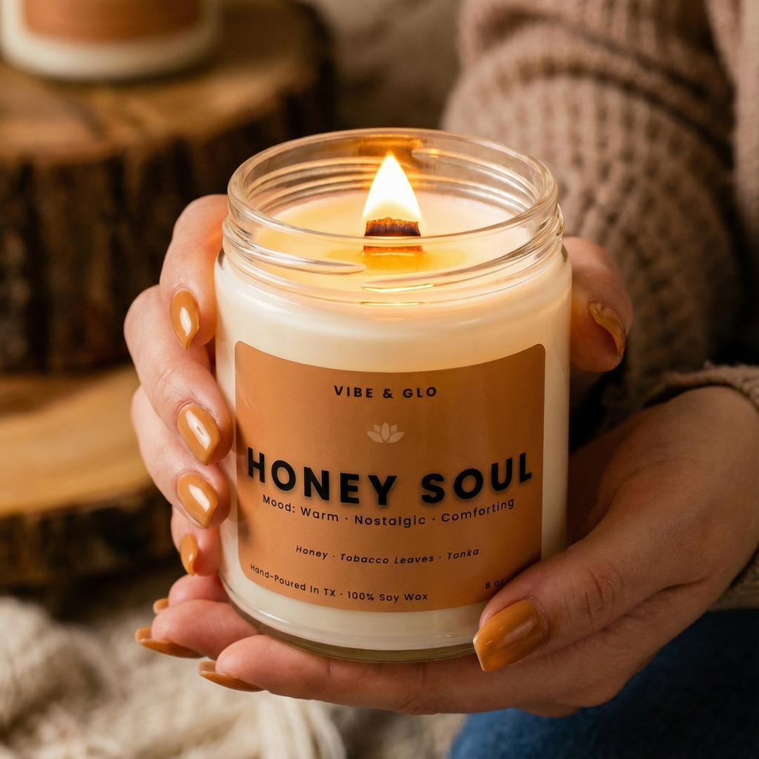 Honey Soul soy candle by Vibe & Glo glowing with a wooden wick, held in hands in a cozy, warm setting