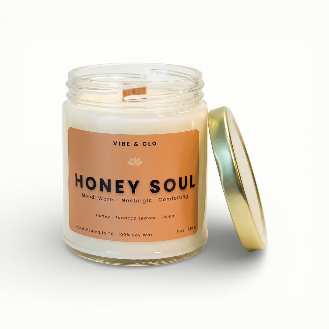 Vibe & Glo Honey Soul soy candle in clear glass jar with wooden wick and gold lid, featuring honey, tobacco leaves, and tonka notes