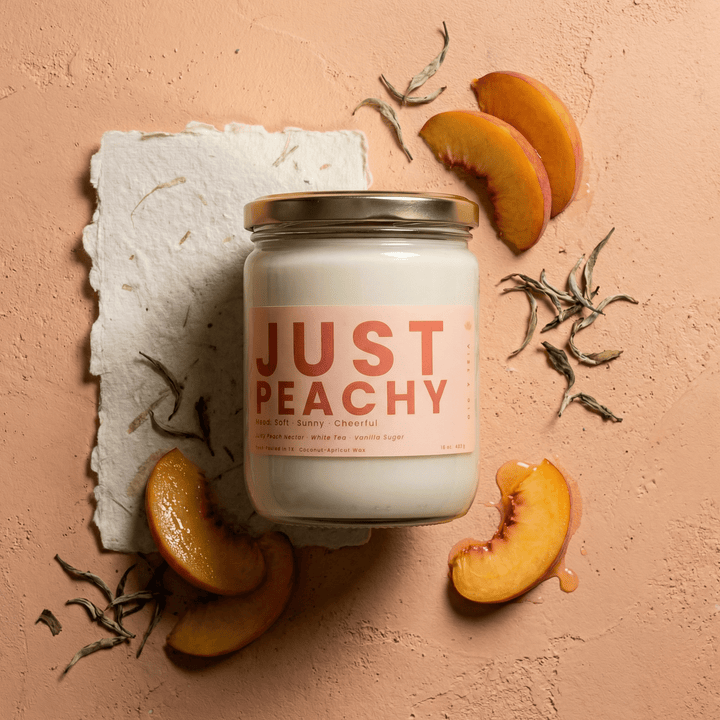 Just Peachy candle styled with fresh peach slices and tea leaves, fruity candle with peach nectar, white tea, and vanilla sugar