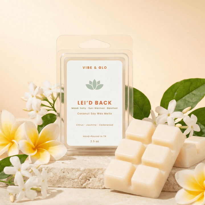 Lei’d Back wax melts with jasmine flowers and greenery styled on stone surface with warm golden lighting