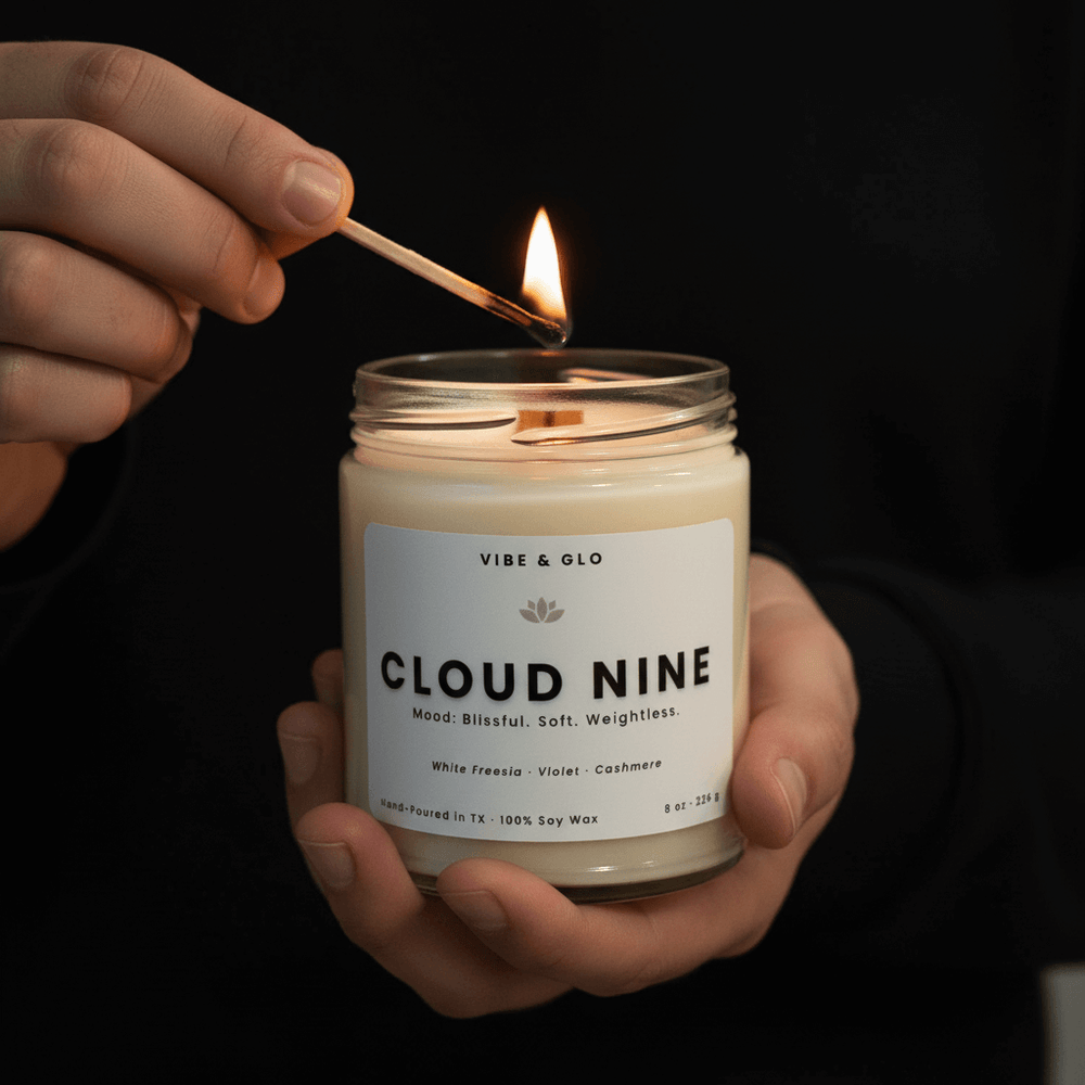 Person lighting a 'Cloud Nine' candle with a match against a dark background