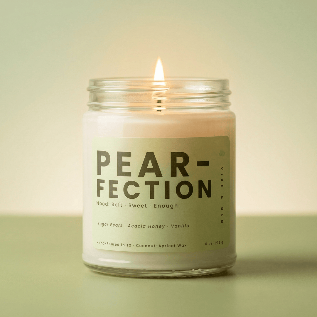 Pear-Fection single wick candle lit in clear glass jar with soft green background highlighting clean burning pear and honey fragrance