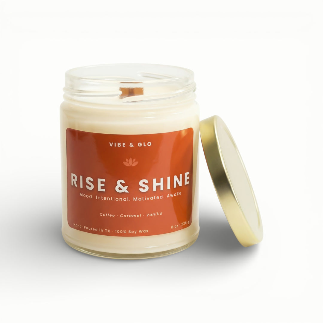 Vibe & Glo Rise & Shine soy candle in clear glass jar with wooden wick and gold lid, coffee caramel vanilla scent for an energizing mood