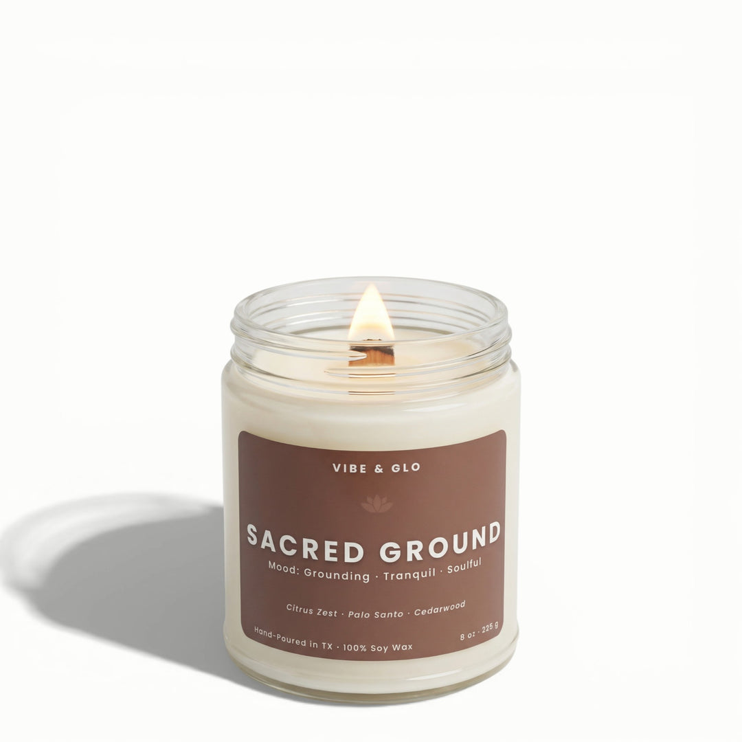 Sacred Ground citrus zest, palo santo, and cedarwood soy candle by Vibe & Glo with lit wooden wick.