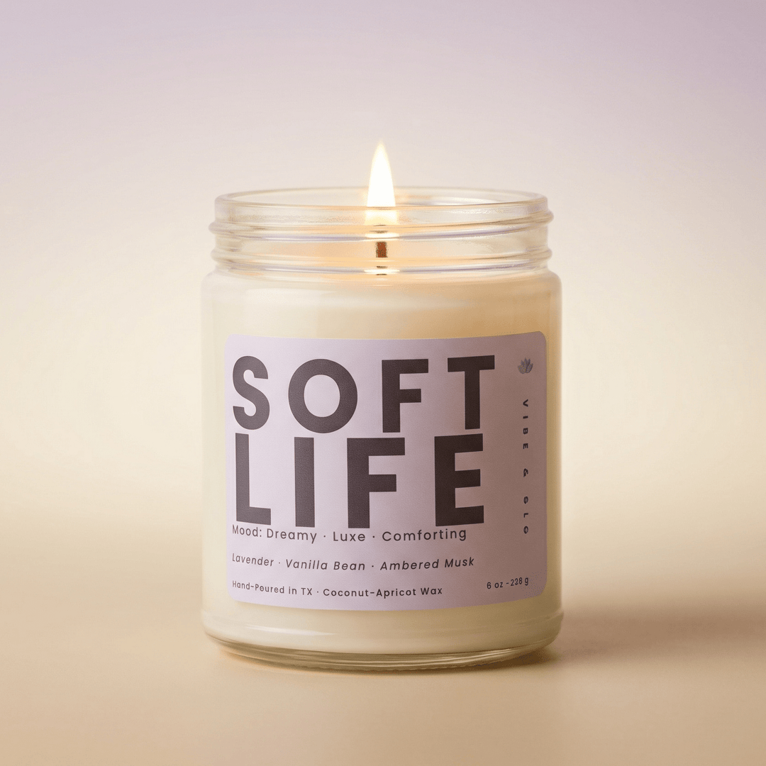 Soft Life coconut apricot wax candle burning in a clear glass jar with lavender vanilla and ambered musk fragrance notes