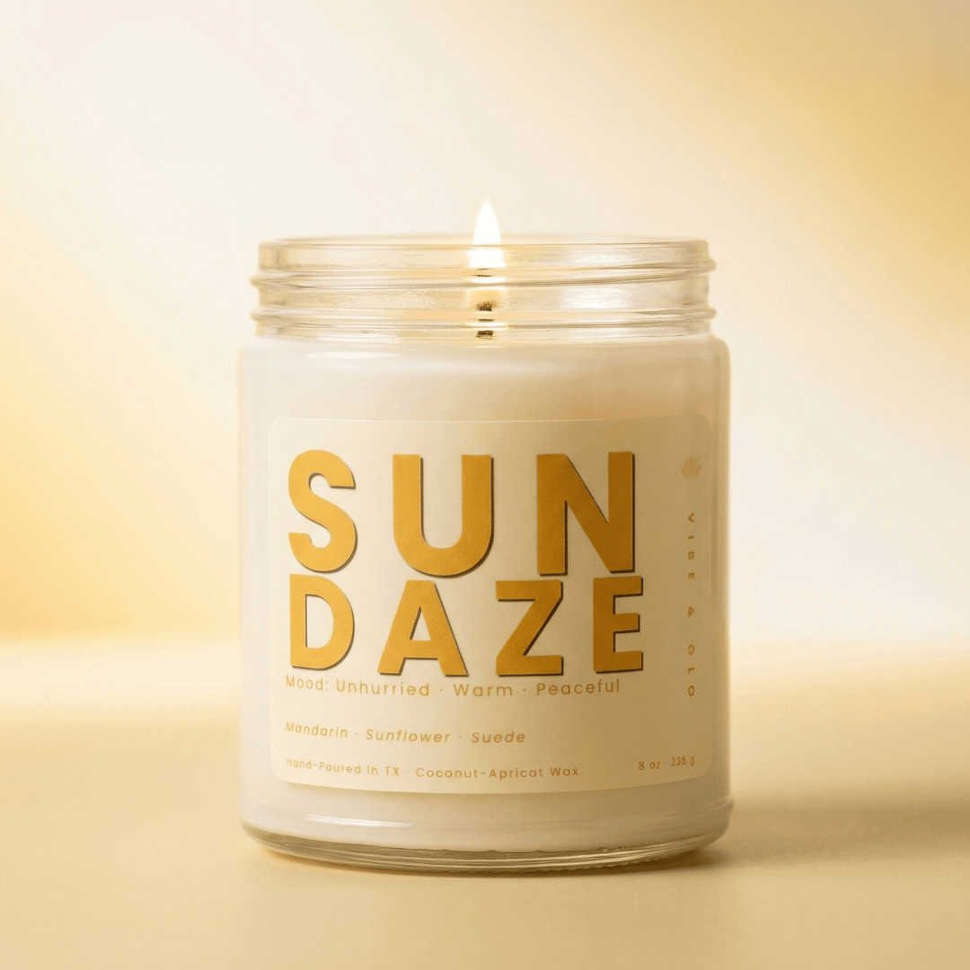 Sun Daze coconut apricot wax candle burning with a soft golden glow featuring warm notes of mandarin sunflower and suede