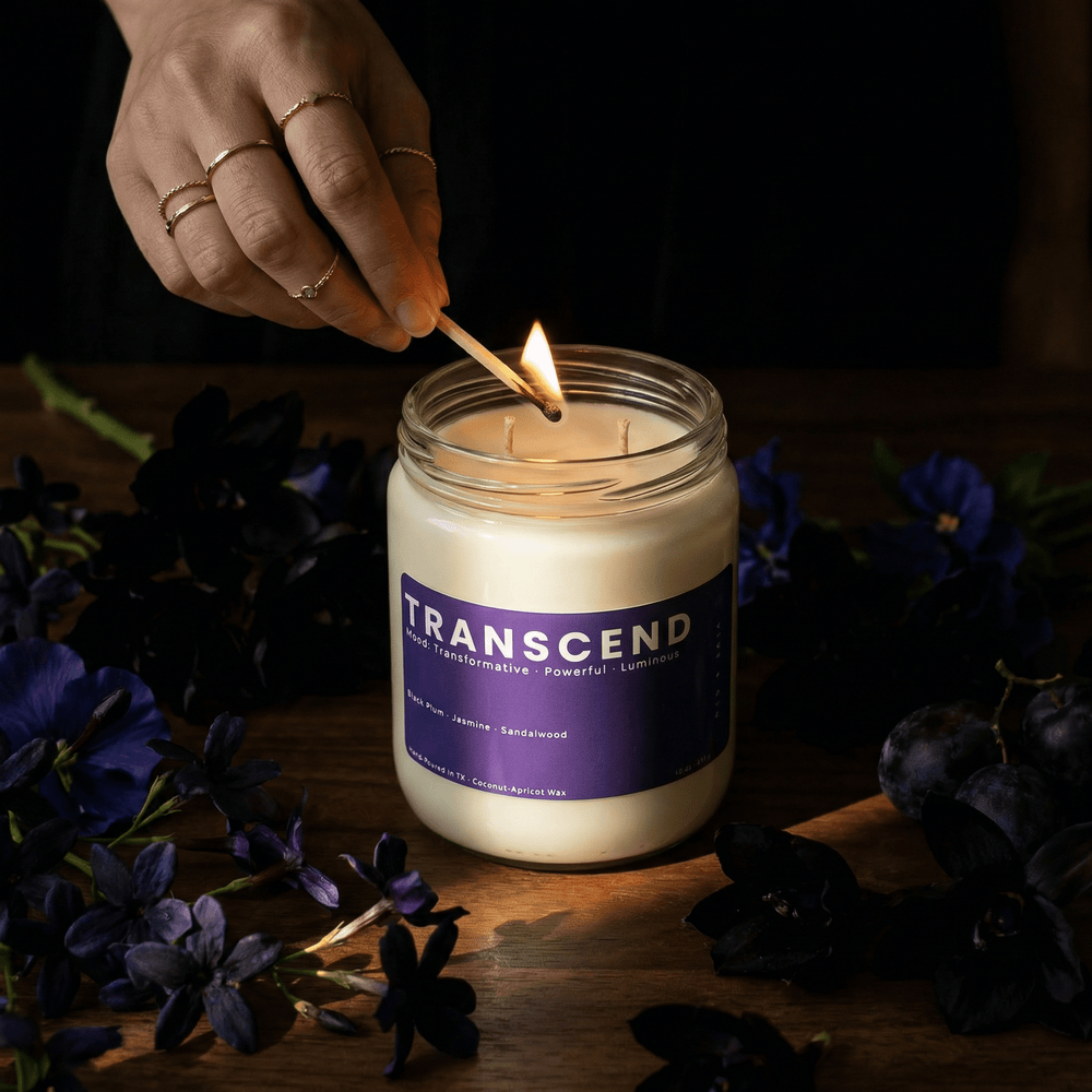 Transcend 2-wick candle being lit with a match in a dark, moody setting with florals, creating a rich and elevated atmosphere