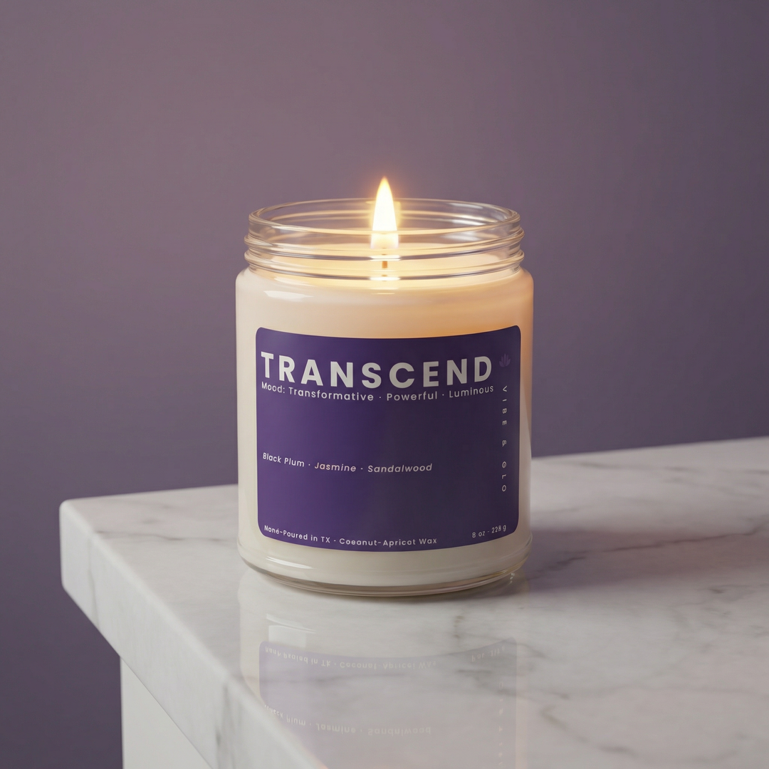 Transcend scented candle in clear glass jar lit on marble surface, clean coconut apricot wax candle with black plum jasmine sandalwood fragrance