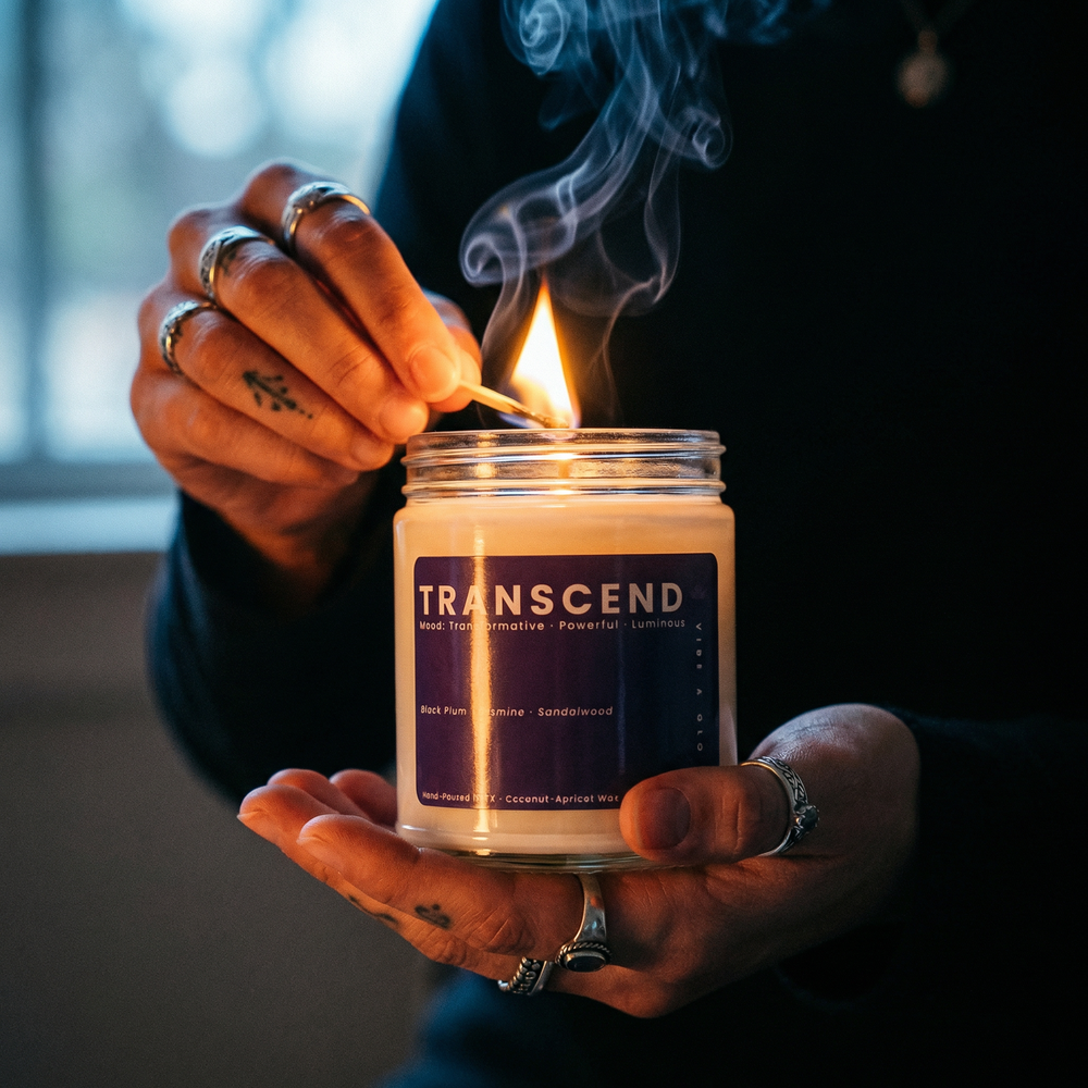Hands lighting Transcend candle with a match creating a moody glowing atmosphere with soft smoke and warm flame