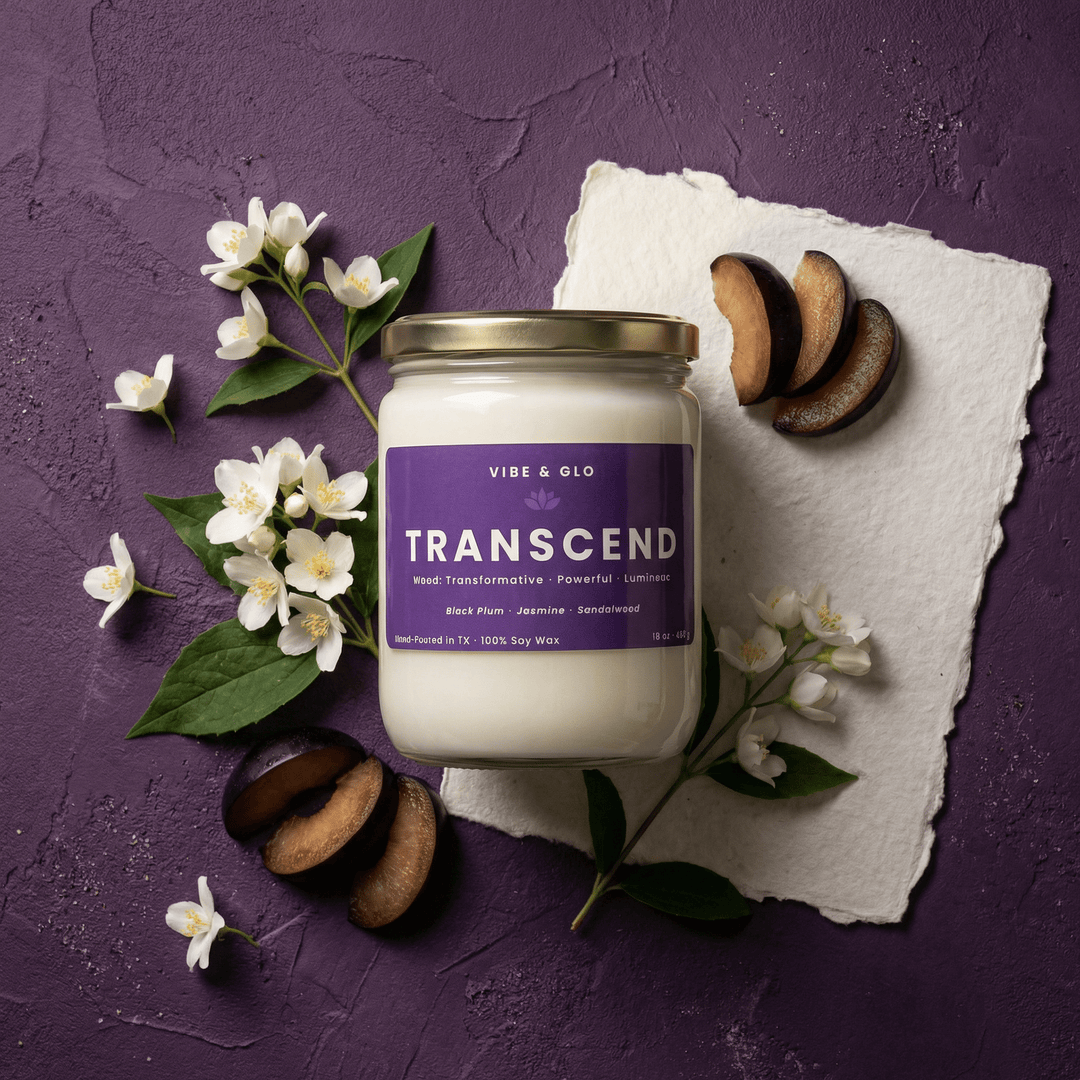 A 16 oz Transcend double wick soy candle by Vibe & Glo styled in a rich purple flatlay with sliced black plums and delicate white jasmine flowers, creating a luxurious and moody home fragrance aesthetic.