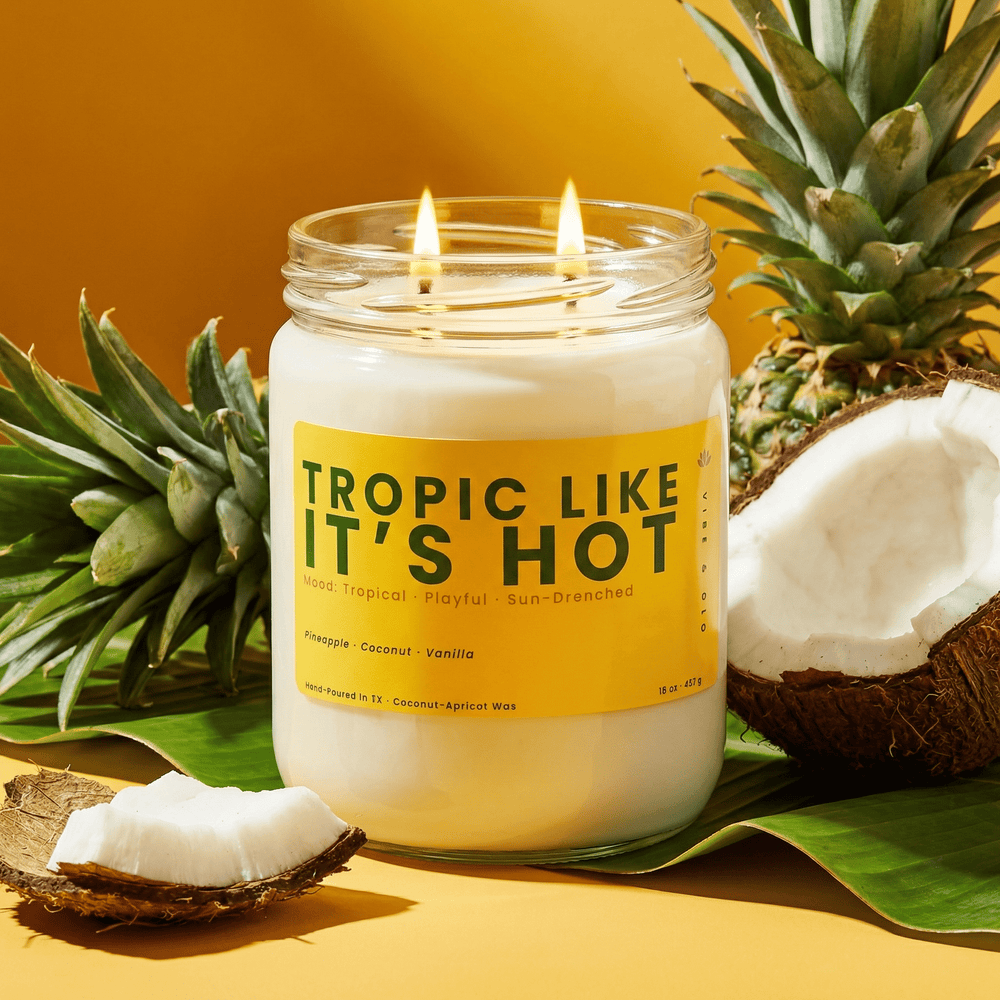 Tropic Like It’s Hot double wick candle styled with pineapple leaves and coconut for tropical summer home fragrance