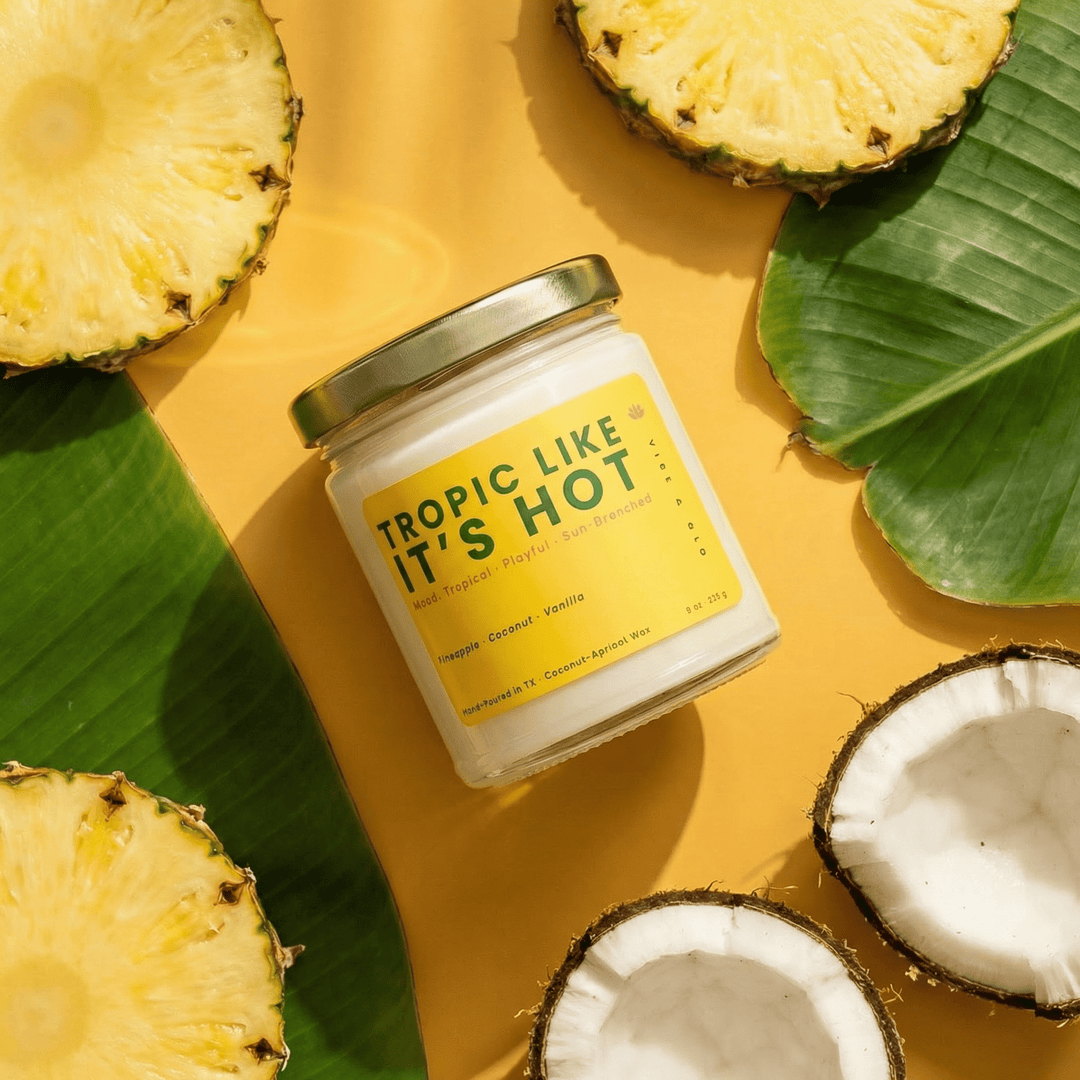 Tropic Like It’s Hot tropical fruit candle styled with pineapple and coconut on a bright yellow background