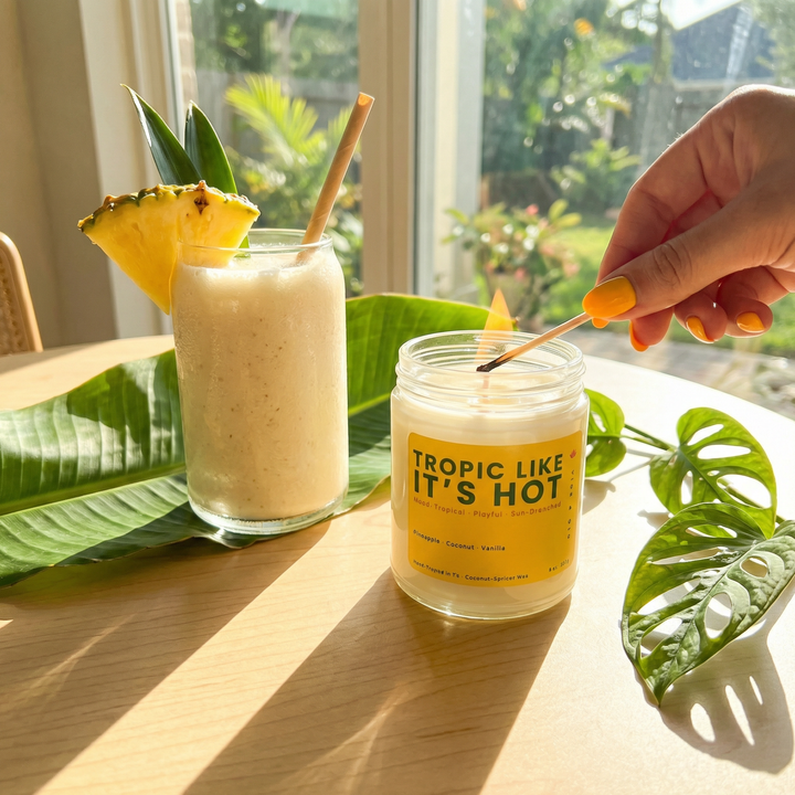 Lighting a tropical fruit candle next to a pineapple drink in a bright summer setting with natural sunlight and greenery