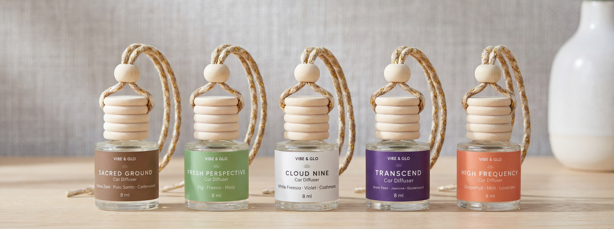 Vibe & Glo car diffusers featuring scented glass bottle air fresheners in Sacred Ground, Fresh Perspective, Cloud Nine, Transcend, and High Frequency