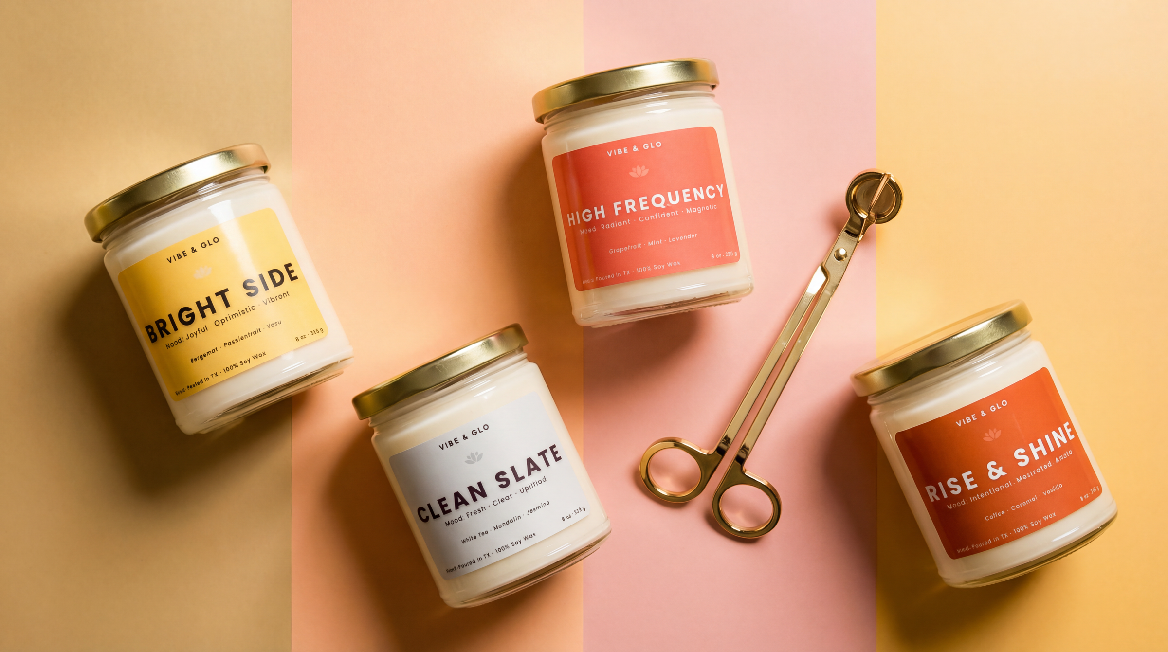 Clean-burning soy candles by Vibe & Glo Candle Studio with gold lids on pastel background flat lay