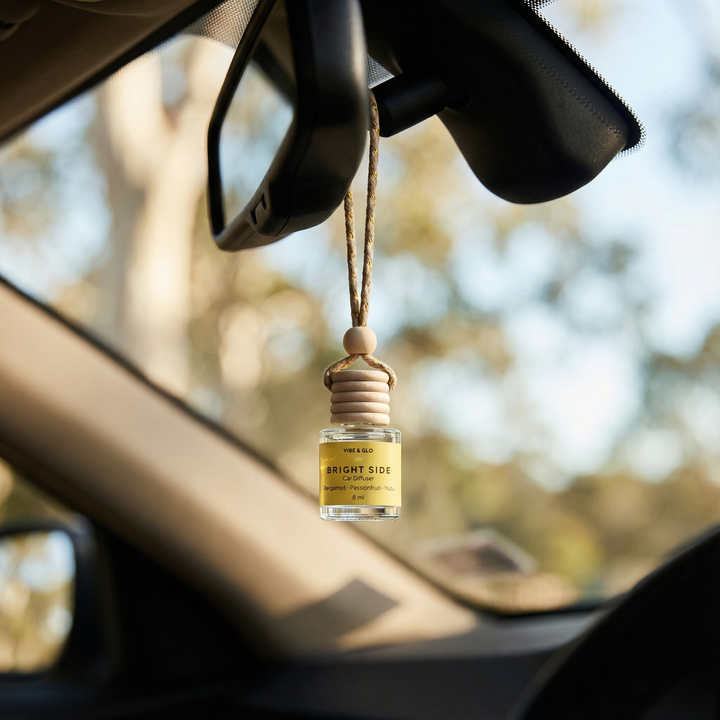 Vibe & Glo hanging car diffuser suspended from a car rearview mirror with visible fragrance oil, creating a bright and uplifting driving experience
