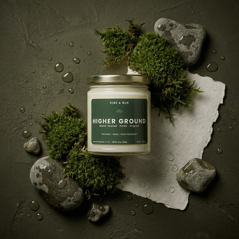 Vibe & Glo Higher Ground 8 oz soy candle with petrichor, moss, and fresh rainwater styled with green moss, smooth river stones, and water droplets on a deep earthy background.